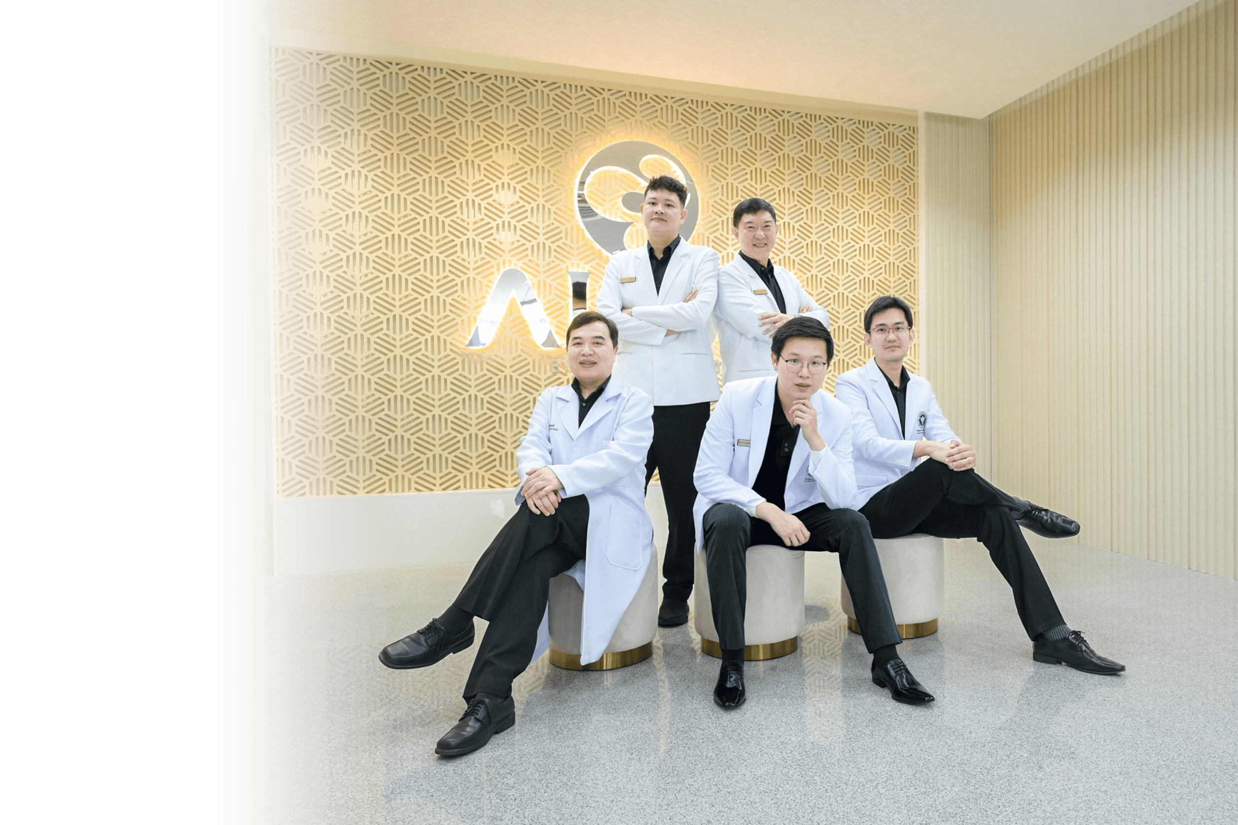 ALIVE clinic medical team — group of doctors seated together in front of the ALIVE wall logo